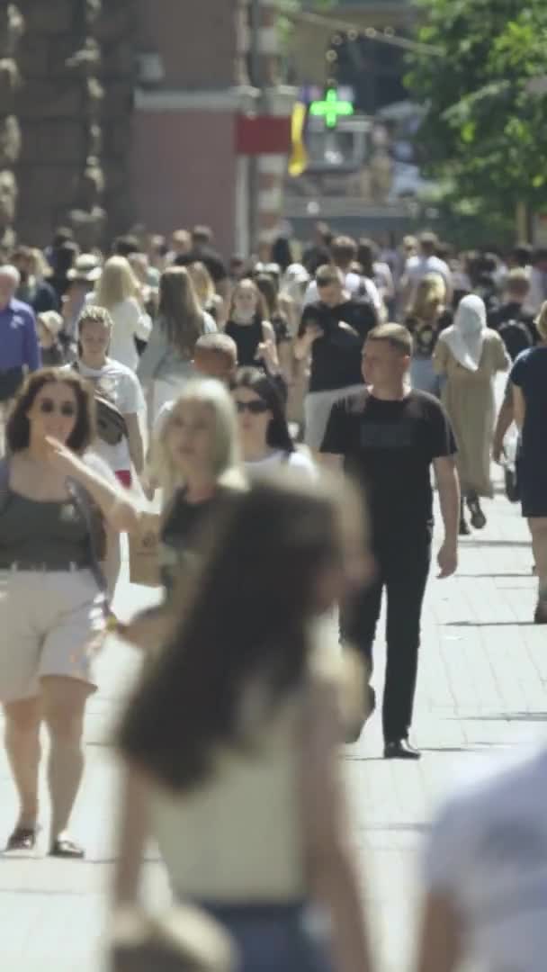 Vertikales Video von vielen Menschen, die in einer Menschenmenge entlang einer Stadtstraße gehen — Stockvideo