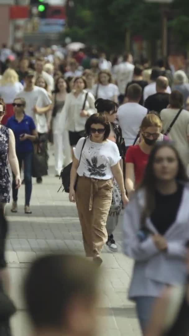 Вертикальное видео многих людей, идущих в толпе по городской улице — стоковое видео