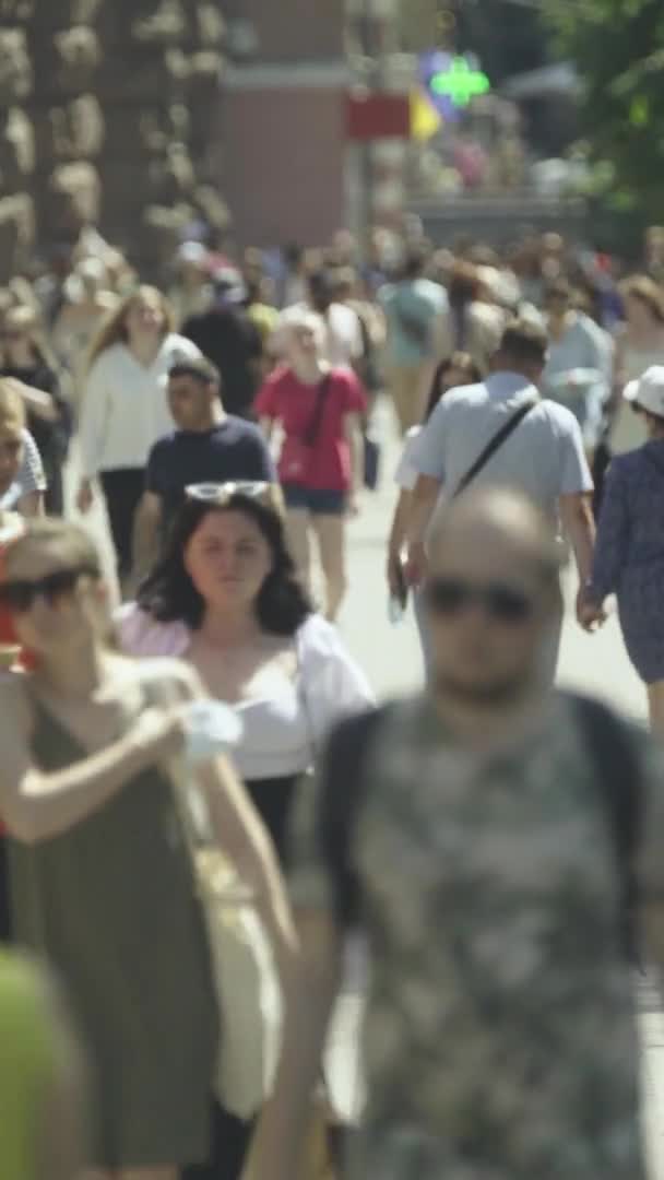 Şehir caddesi boyunca kalabalık içinde yürüyen bir sürü insanın dikey videosu. — Stok video