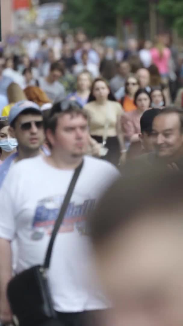 Şehir caddesi boyunca kalabalık içinde yürüyen bir sürü insanın dikey videosu. — Stok video