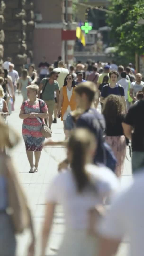 Vertikales Video von vielen Menschen, die in einer Menschenmenge entlang einer Stadtstraße gehen — Stockvideo