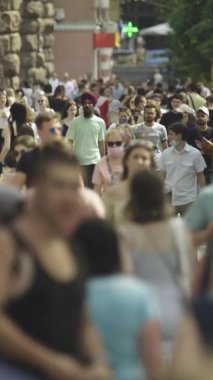 Şehir caddesi boyunca kalabalık içinde yürüyen bir sürü insanın dikey videosu.