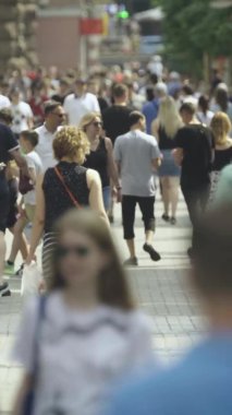 Şehir caddesi boyunca kalabalık içinde yürüyen bir sürü insanın dikey videosu.