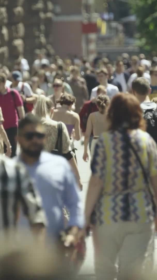 Şehir caddesi boyunca kalabalık içinde yürüyen bir sürü insanın dikey videosu. — Stok video