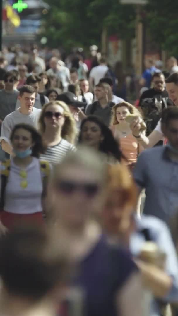 Vertikales Video von vielen Menschen, die in einer Menschenmenge entlang einer Stadtstraße gehen — Stockvideo