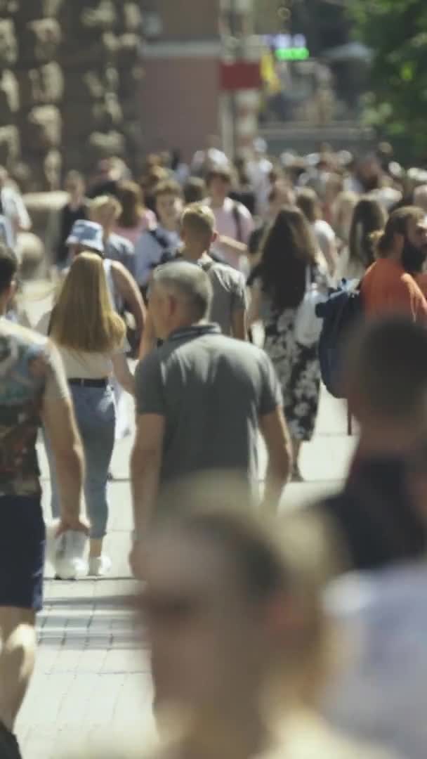 Şehir caddesi boyunca kalabalık içinde yürüyen bir sürü insanın dikey videosu. — Stok video
