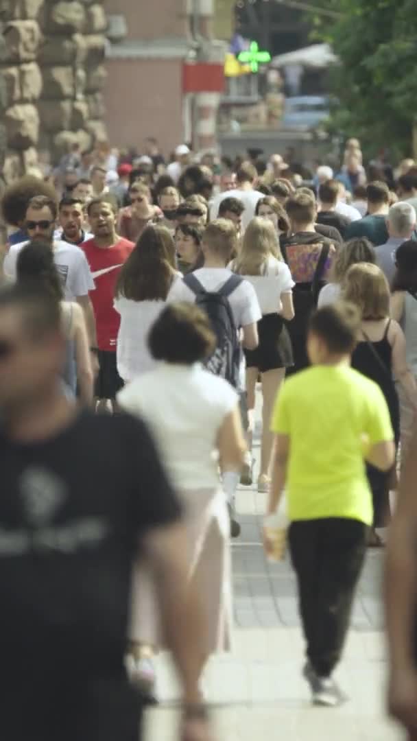 Lodret video af mange mennesker gå i en menneskemængde langs en bygade – Stock-video