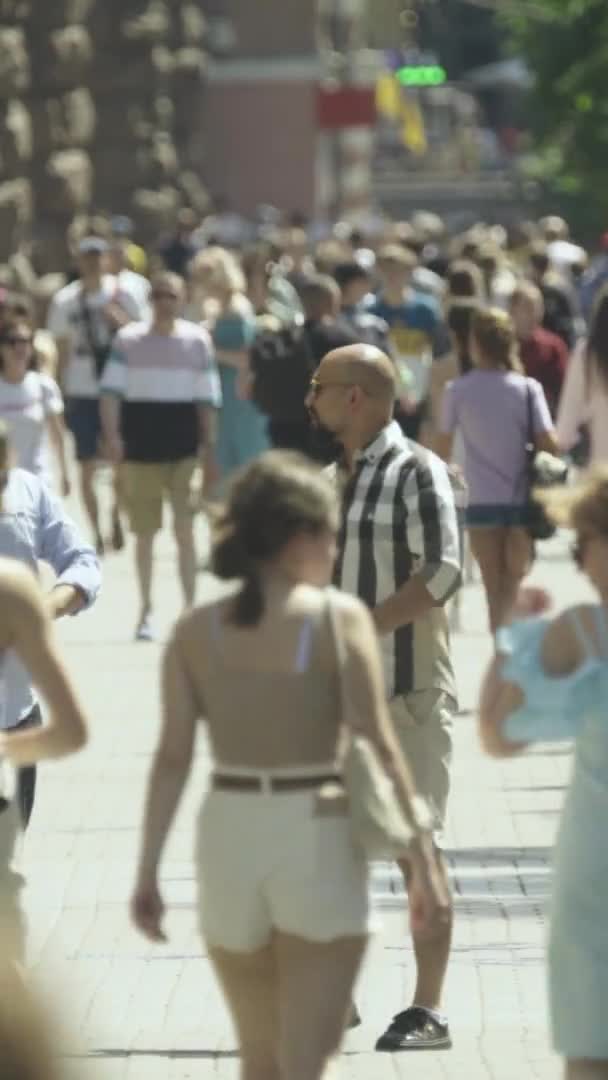 Şehir caddesi boyunca kalabalık içinde yürüyen bir sürü insanın dikey videosu. — Stok video