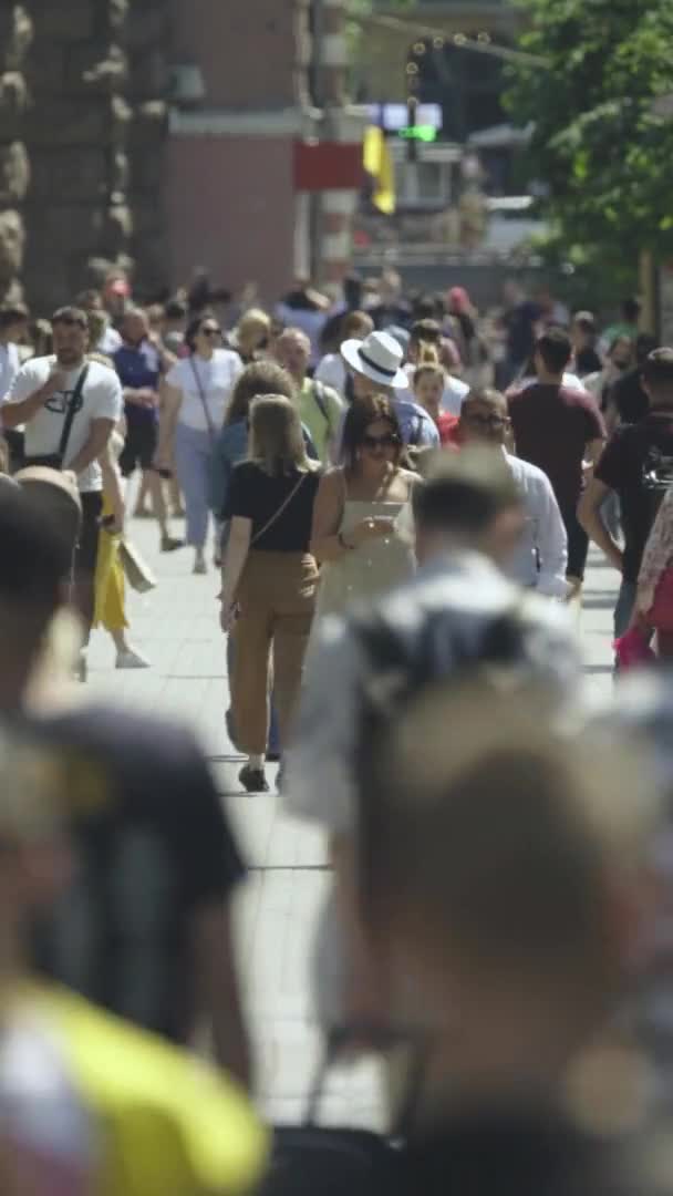 Vertikales Video von vielen Menschen, die in einer Menschenmenge entlang einer Stadtstraße gehen — Stockvideo