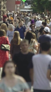 Şehir caddesi boyunca kalabalık içinde yürüyen bir sürü insanın dikey videosu.