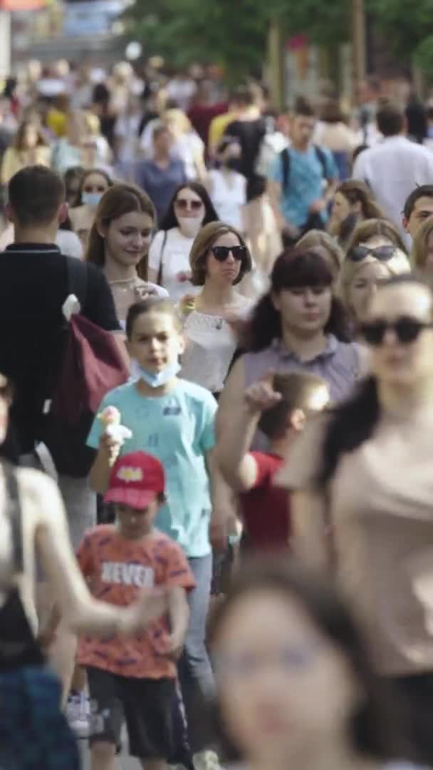 Вертикальное видео многих людей, идущих в толпе по городской улице — стоковое видео