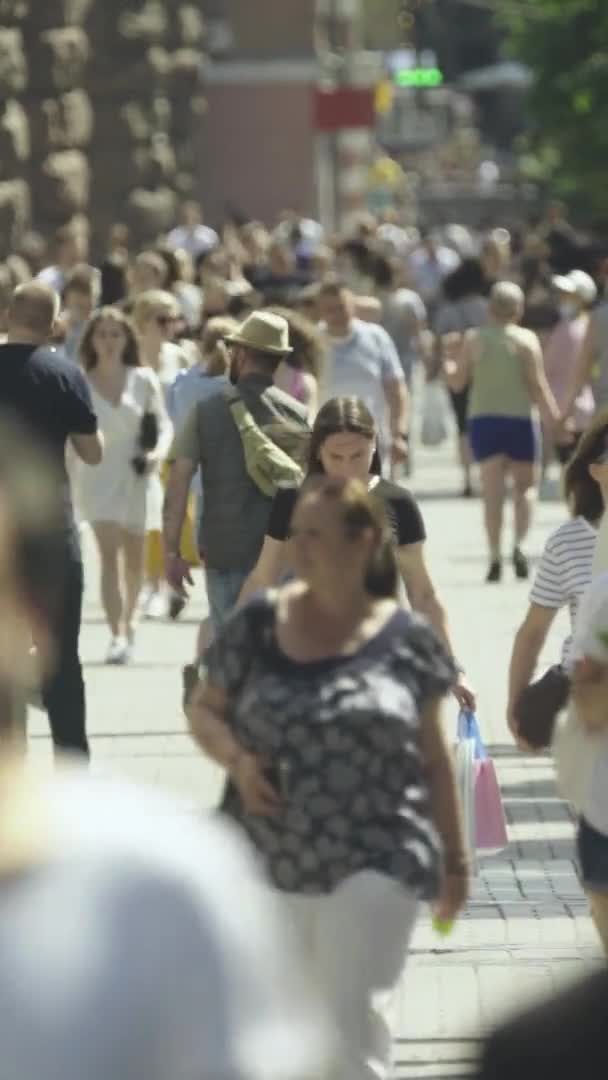 Verticale video van veel mensen die in een menigte langs een straat lopen — Stockvideo