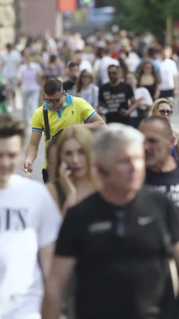 Şehir caddesi boyunca kalabalık içinde yürüyen bir sürü insanın dikey videosu. — Stok video