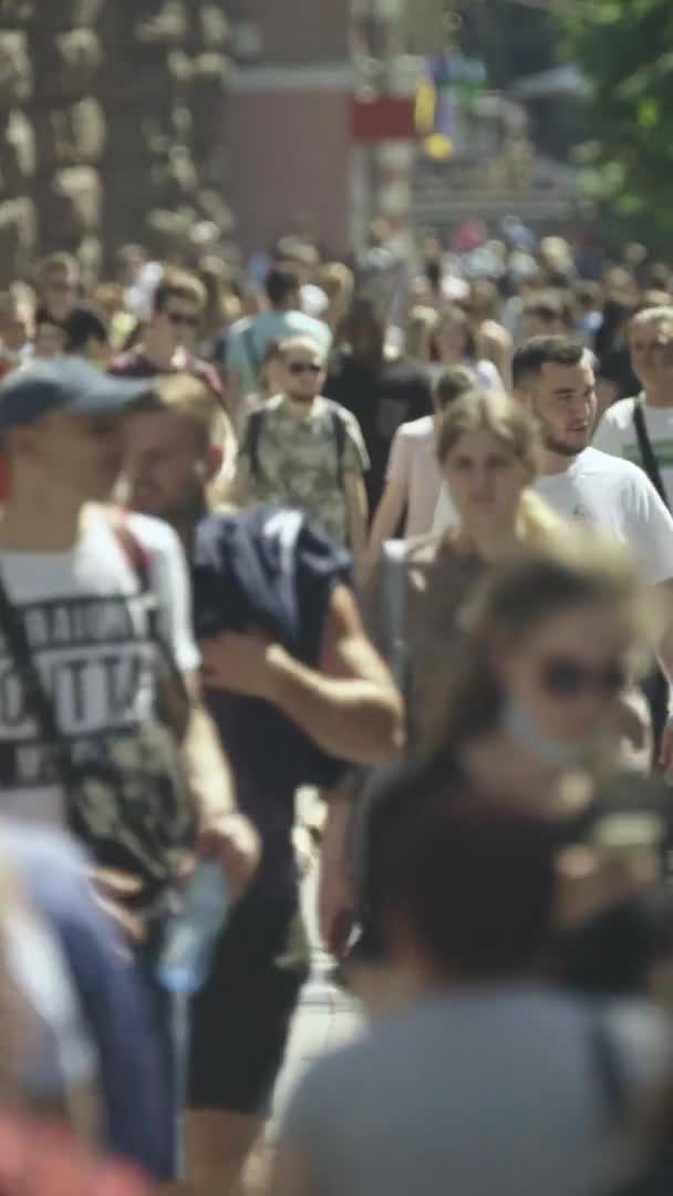 Şehir caddesi boyunca kalabalık içinde yürüyen bir sürü insanın dikey videosu. — Stok video