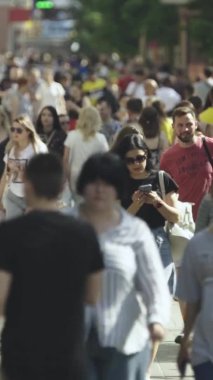 Gün boyunca kalabalık bir şehir sokağının dikey videosu