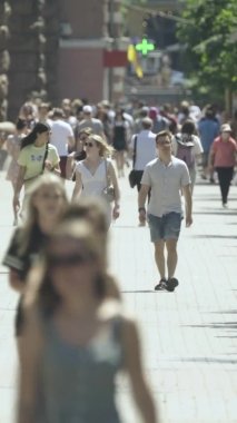 Gün boyunca kalabalık bir şehir sokağının dikey videosu