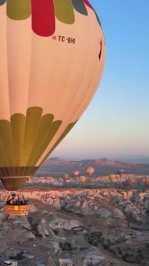 Türkiye 'nin Kapadokya üzerinde gökyüzünde uçan sıcak hava balonlarının dikey videosu.