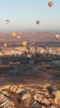 Türkiye 'nin Kapadokya üzerinde gökyüzünde uçan sıcak hava balonlarının dikey videosu.
