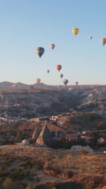 Türkiye 'nin Kapadokya üzerinde gökyüzünde uçan sıcak hava balonlarının dikey videosu.