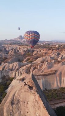 Türkiye 'nin Kapadokya üzerinde gökyüzünde uçan sıcak hava balonlarının dikey videosu.