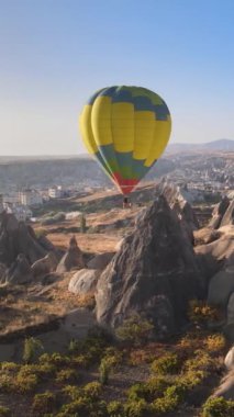 Türkiye 'nin Kapadokya üzerinde gökyüzünde uçan sıcak hava balonlarının dikey videosu.