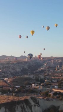 Türkiye 'nin Kapadokya üzerinde gökyüzünde uçan sıcak hava balonlarının dikey videosu.