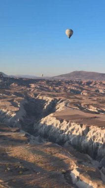 Türkiye 'nin Kapadokya üzerinde gökyüzünde uçan sıcak hava balonlarının dikey videosu.
