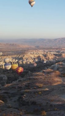 Türkiye 'nin Kapadokya üzerinde gökyüzünde uçan sıcak hava balonlarının dikey videosu.
