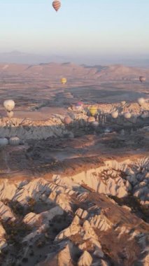 Türkiye 'nin Kapadokya üzerinde gökyüzünde uçan sıcak hava balonlarının dikey videosu.
