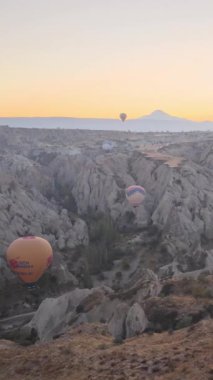 Türkiye 'nin Kapadokya üzerinde gökyüzünde uçan sıcak hava balonlarının dikey videosu.