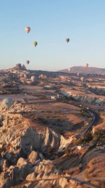 Türkiye 'nin Kapadokya üzerinde gökyüzünde uçan sıcak hava balonlarının dikey videosu.