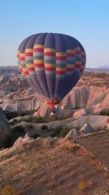 Türkiye 'nin Kapadokya üzerinde gökyüzünde uçan sıcak hava balonlarının dikey videosu.