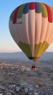 Türkiye 'nin Kapadokya üzerinde gökyüzünde uçan sıcak hava balonlarının dikey videosu.