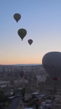 Türkiye 'nin Kapadokya üzerinde gökyüzünde uçan sıcak hava balonlarının dikey videosu.