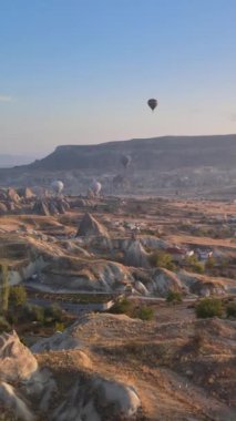Türkiye 'nin Kapadokya üzerinde gökyüzünde uçan sıcak hava balonlarının dikey videosu.