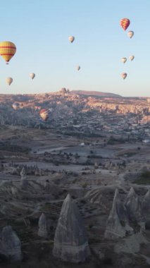 Türkiye 'nin Kapadokya üzerinde gökyüzünde uçan sıcak hava balonlarının dikey videosu.