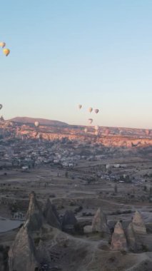 Türkiye 'nin Kapadokya üzerinde gökyüzünde uçan sıcak hava balonlarının dikey videosu.