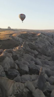 Türkiye 'nin Kapadokya üzerinde gökyüzünde uçan sıcak hava balonlarının dikey videosu.