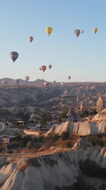 Türkiye 'nin Kapadokya üzerinde gökyüzünde uçan sıcak hava balonlarının dikey videosu.