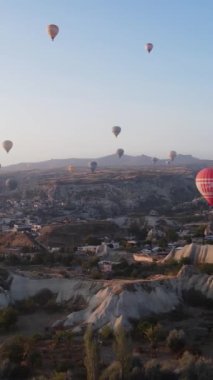 Türkiye 'nin Kapadokya üzerinde gökyüzünde uçan sıcak hava balonlarının dikey videosu.