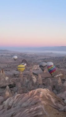 Türkiye 'nin Kapadokya üzerinde gökyüzünde uçan sıcak hava balonlarının dikey videosu.