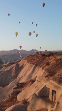 Türkiye 'nin Kapadokya üzerinde gökyüzünde uçan sıcak hava balonlarının dikey videosu.