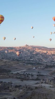 Türkiye 'nin Kapadokya üzerinde gökyüzünde uçan sıcak hava balonlarının dikey videosu.
