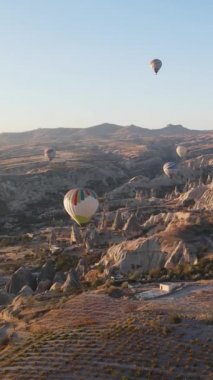 Türkiye 'nin Kapadokya üzerinde gökyüzünde uçan sıcak hava balonlarının dikey videosu.