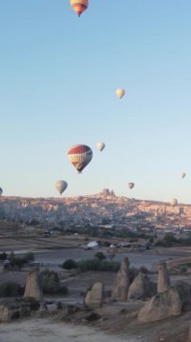 Türkiye 'nin Kapadokya üzerinde gökyüzünde uçan sıcak hava balonlarının dikey videosu.