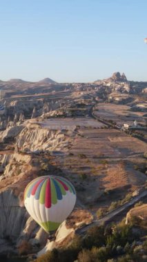 Türkiye 'nin Kapadokya üzerinde gökyüzünde uçan sıcak hava balonlarının dikey videosu.