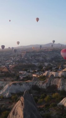 Türkiye 'nin Kapadokya üzerinde gökyüzünde uçan sıcak hava balonlarının dikey videosu.