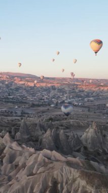 Türkiye 'nin Kapadokya üzerinde gökyüzünde uçan sıcak hava balonlarının dikey videosu.