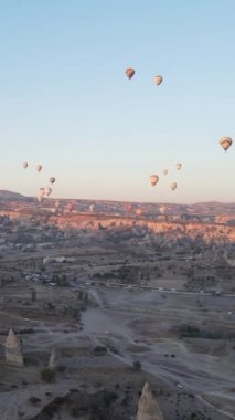 Türkiye 'nin Kapadokya üzerinde gökyüzünde uçan sıcak hava balonlarının dikey videosu.