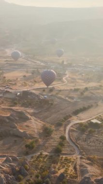 Türkiye 'nin Kapadokya üzerinde gökyüzünde uçan sıcak hava balonlarının dikey videosu.